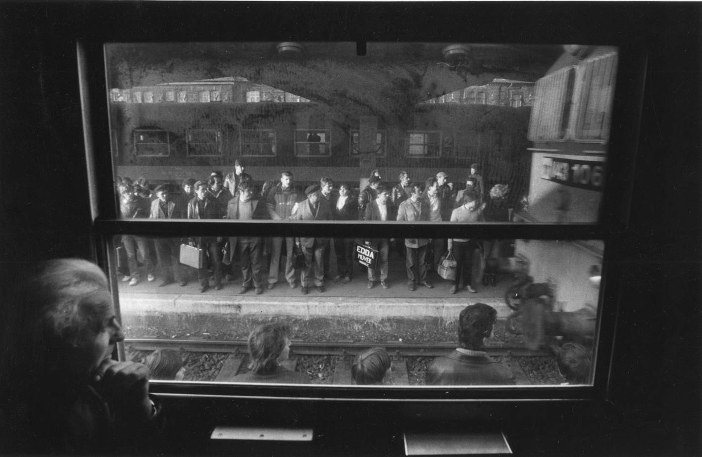 Bahnhof Miskolc: Menschen warten auf dem Bahnsteig auf die Einfahrt eines Arbeiterzuges. Links unten im Bild ist András Skarbit, die Hauptfigur der zwischen 1978 und 1988 erstellten Fotoreihe, zu sehen.