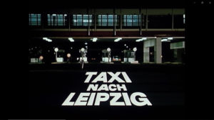 Ein Filmstill aus der „Tatort“-Folge „Taxi nach Leipzig“ zeigt den Grenzübergang und den Titel der Folge.