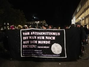 Viele Menschen halten ein Plakat, auf dem ein Zitat von Hannah Arendt zu sehen ist: "Vor Antisemitismus ist man nur noch auf dem Monde sicher!" Auch weitere Parolen gegen antisemitische Gewalt sind zu sehen.