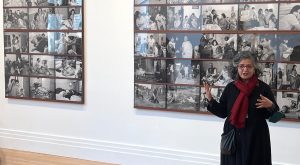 Dayanita Singh vor einer Ausstellungswand mit vielen Bildern in schwarz-weiß.