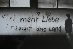 Eine Person betrachtet ein Graffiti mit den Worten "Viel mehr Liebe braucht das Land"