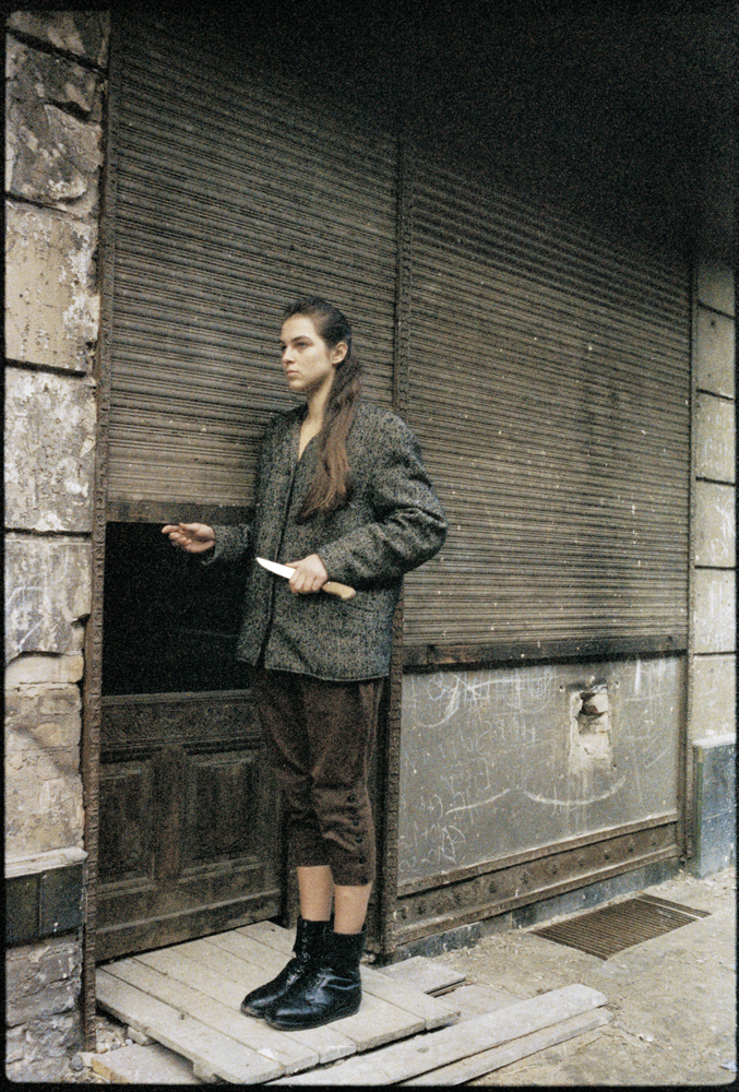 Eine Frau steht vor einem Eingang mit heruntergezogenen Rollläden.