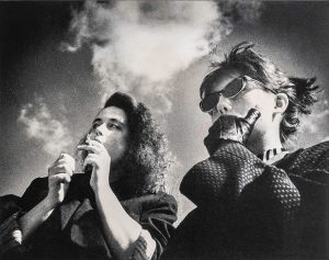 Bild von zwei Frauen, die eine Zigarette rauchen und in die Ferne schauen.