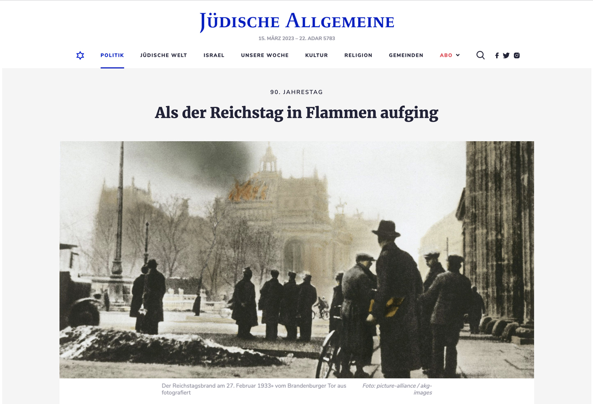 Screenshot der Website der „Jüdischen Allgemeine“ mit einem Foto vom Berliner Reichstag: Mehrere Menschen stehen alleine und in Gruppen auf der Straße und blicken auf ein Gebäude, aus dessen Kuppel Qualm aufsteigt, auch orange nachkolorierte Flammen sind zu erkennen.