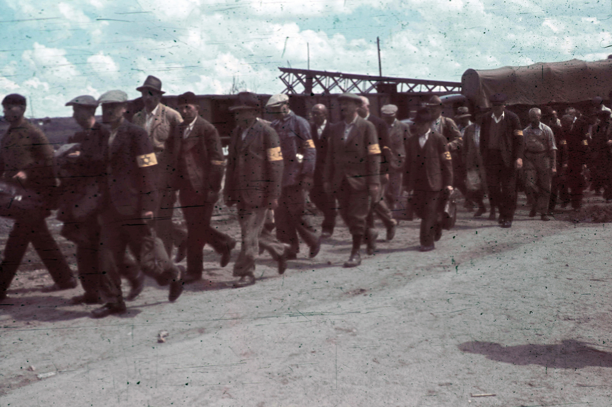 Eine Gruppe von Männern mit gelben Armbinden mit dem sogenannten Judenstern auf einem Weg