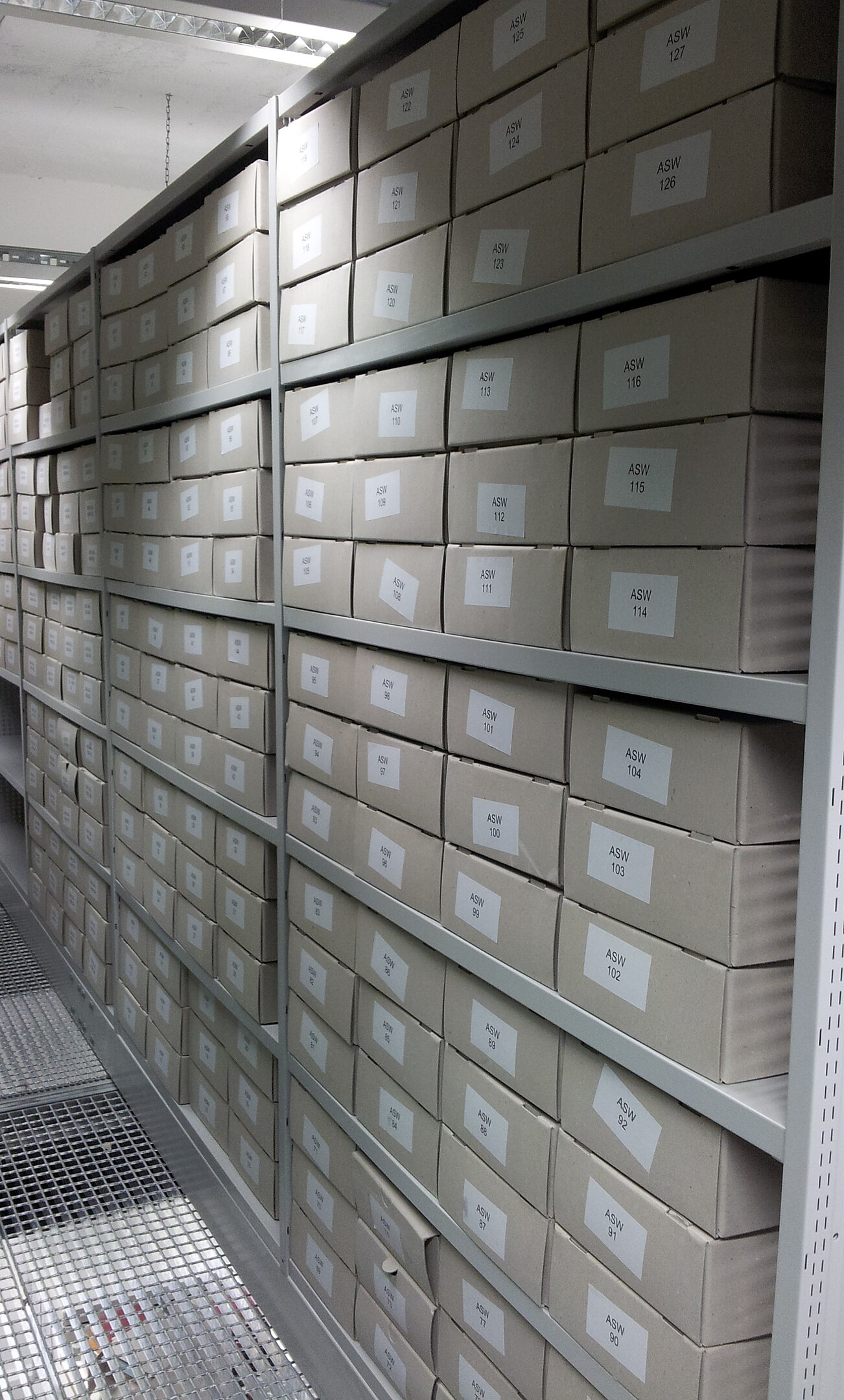 mehrere graue Archivkartons übereinander gestapelt im Regal