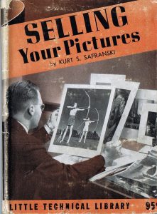 Buchcover: Unter dem Titel – schwarze Schrift auf rotbraunem Untergrund – befindet sich das Foto eines Mannes: Er ist von hinten an seinem Schreibtisch zu sehen, wie er mehrere Fotografien betrachtet; eine zeigt zwei Personen, die mit dem Bogen schießen.
