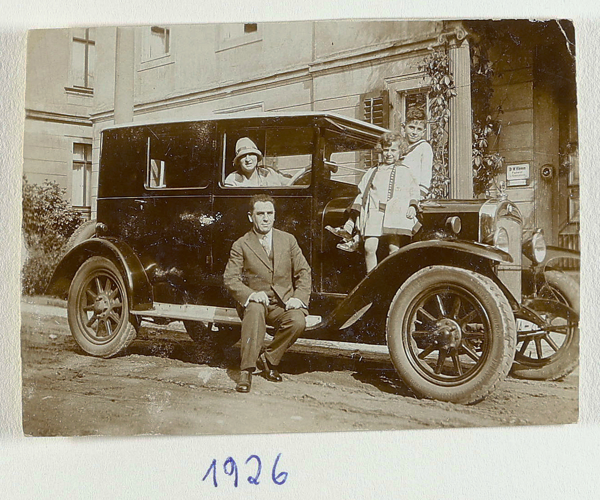 Familie posiert auf einem Auto für ein Foto