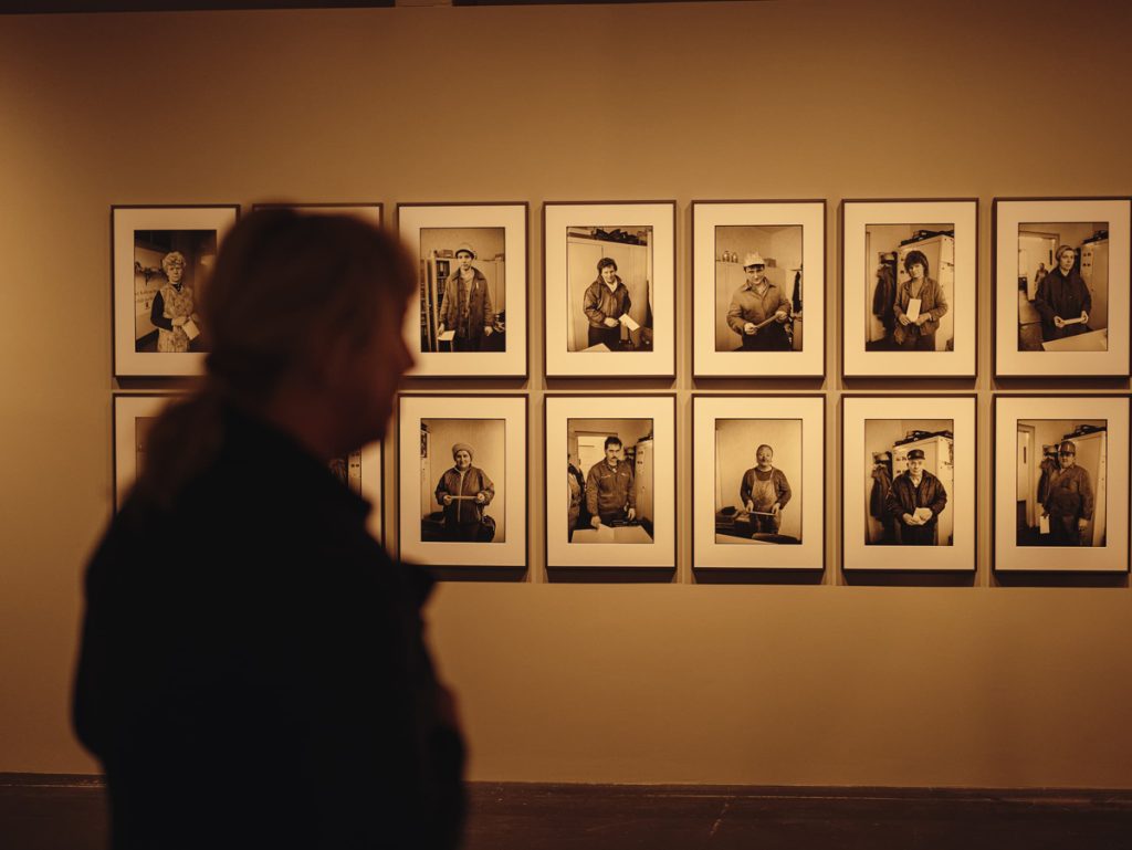 Mann vor einer Wand mit Fotografien