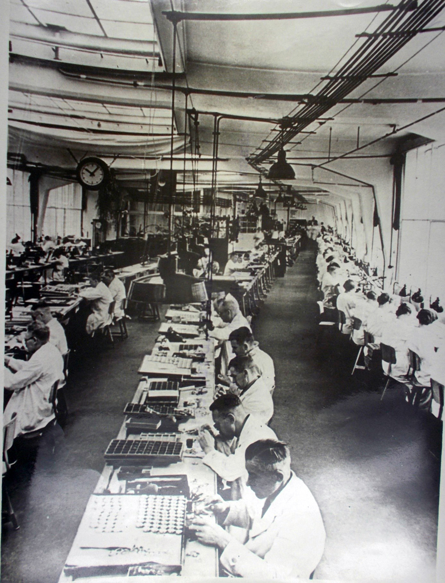 Foto von an Tischen arbeitenden Menschen in einer Werkhalle