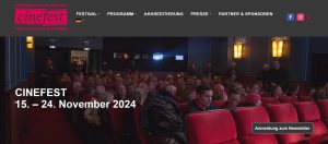 Website-Screenshot mit dem Bild eines Kinosaals voll mit Menschen; darüber Schrift