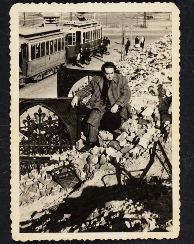 Mann sitzend in Ruinen, hinter ihm eine Straßenbahn