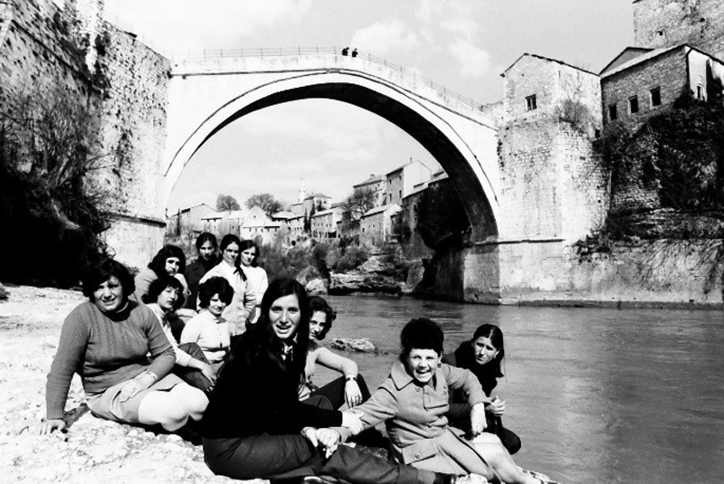 Foto einer Gruppe von Frauen an einem Fluss vor einer Brücke