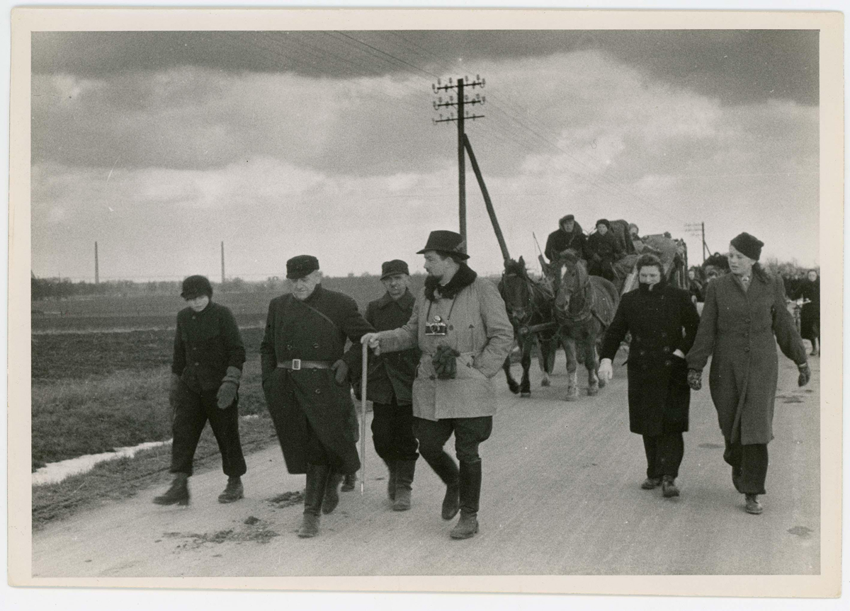 Der Flüchtlingstreck auf der Straße, zwei Männer gehen dem Treck voraus