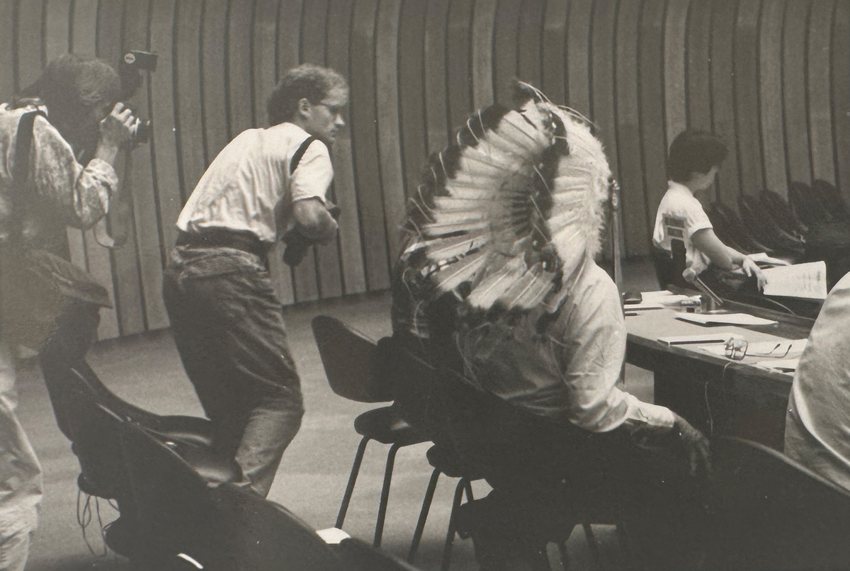 Schwarzweißfoto von zwei Fotografen, die einen Mann mit Kopfschmuck fotografieren.