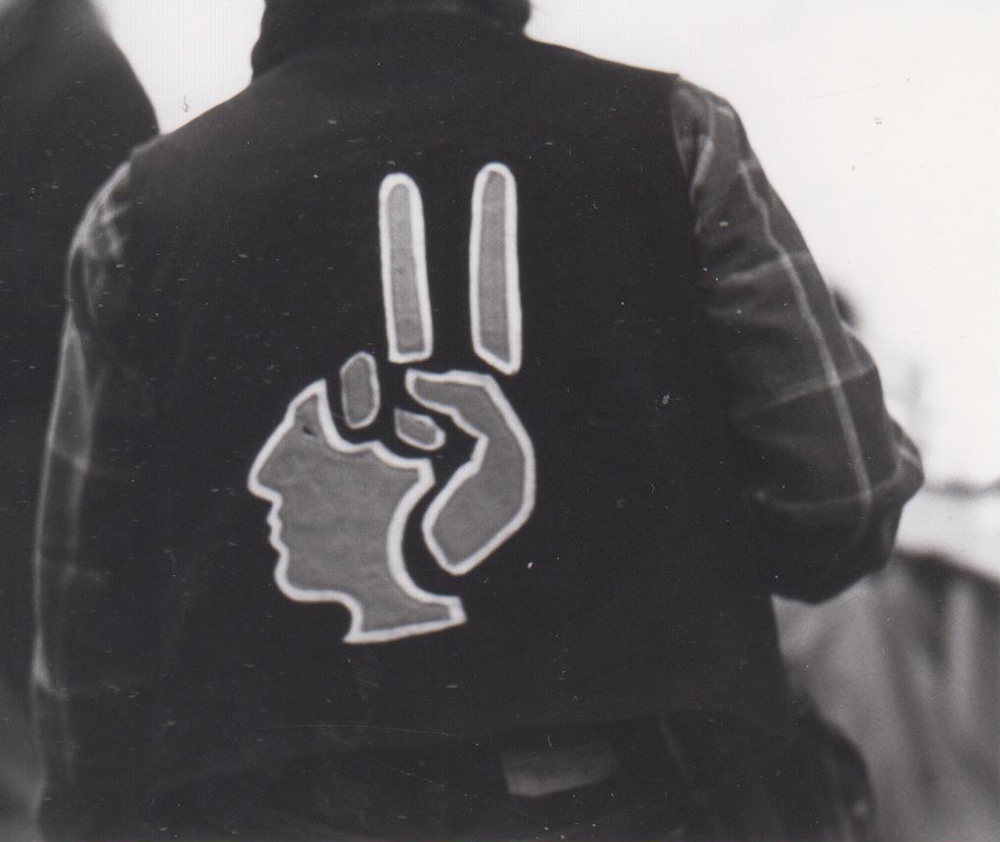 Schwarzweißfoto eines Mannes von hinten mit einer Weste mit Logo