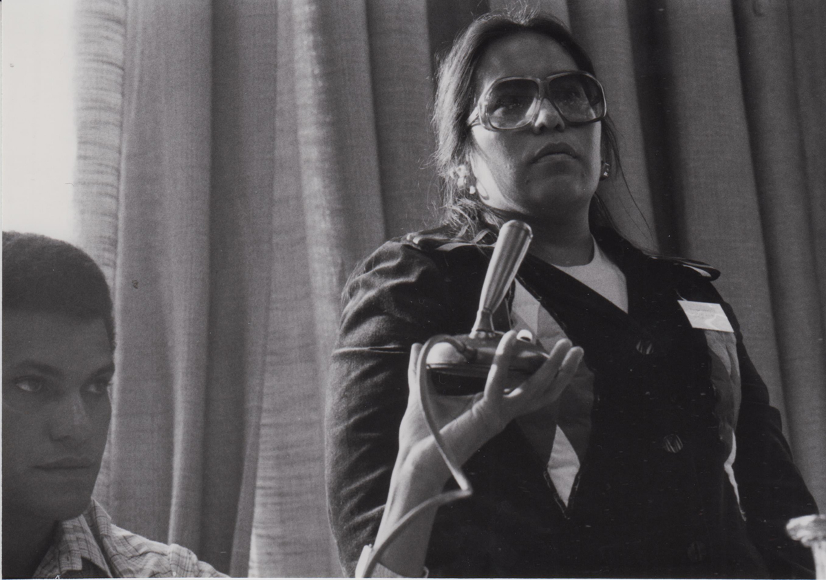 Schwarzweißfoto von einer stehenden Frau, daneben ein sitzender Mann