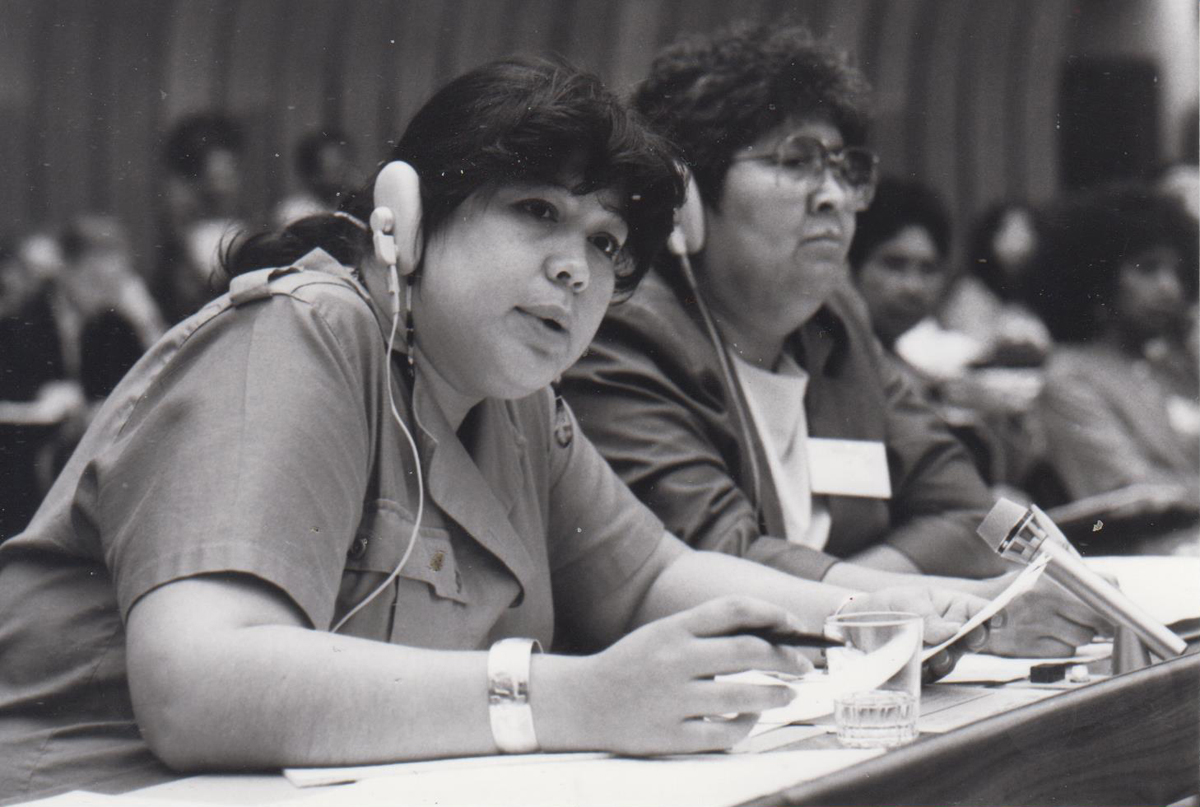 Schwarzweißfoto von zwei Frauen an einem Konferenztisch mit Kopfhörern