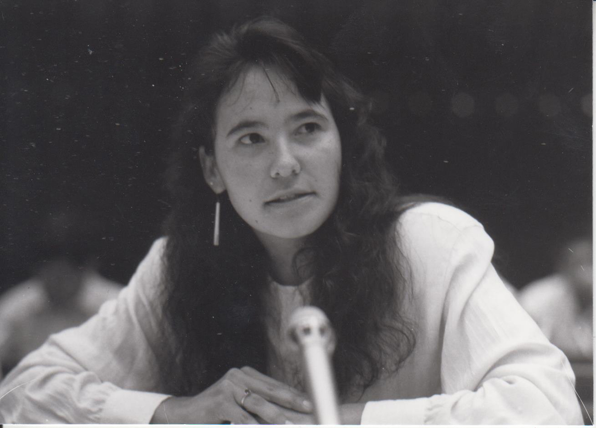 Schwarzweißfoto einer sitzenden Frau vor einem Mikrofon