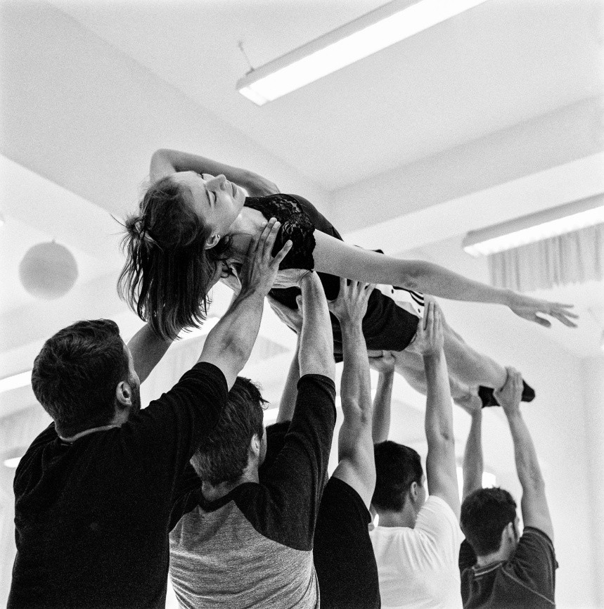 Schwarzweißfotografie von fünf Männern, die eine Frau in die Höhe halten