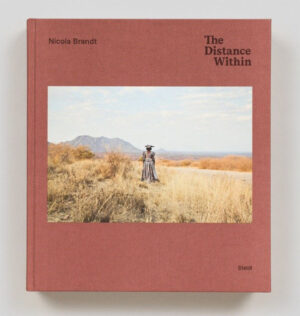 Roter Umschlag mit farbiger Fotografie einer Frau von hinten in einer Graslandschaft mit einem Berg im Hintergrund