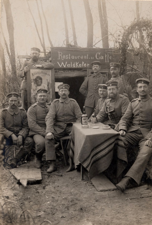 Schwarzweißfoto von Männern in Uniform an einem Tisch vor einem Unterstand