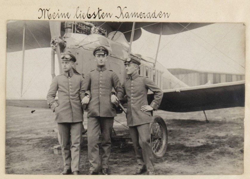 Schwarzweißfoto von drei Männern in Uniform vor einem Flugzeug
