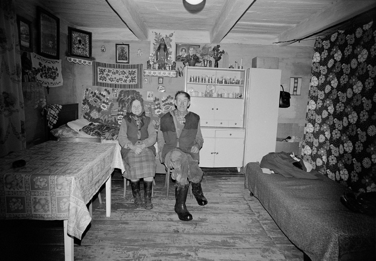 Schwarzweißfoto eines sitzenden älteren Paares in einem kleinen Zimmer